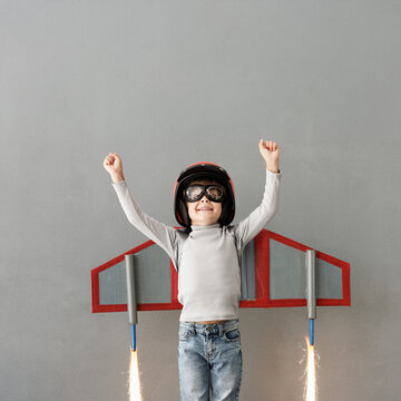 Happy child pretend to be astronaut. Funny kid with paper rocket. Little boy playing indoors