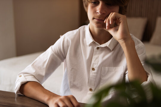 Tired male teenager at home, contemplating during remote education, feeling boredom and lacking motivation while studying from his bedroom