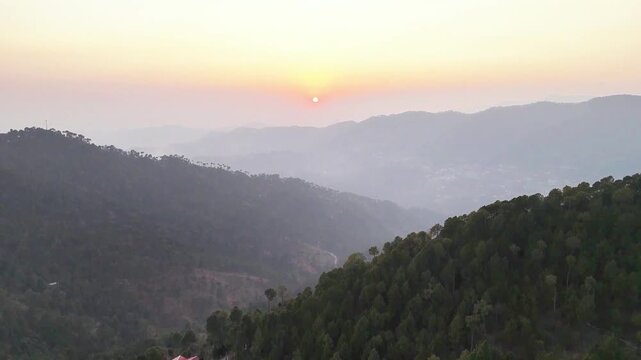Scenic Aerial View of Golden Sunset Over Misty Mountain Ridges and Pine Forests