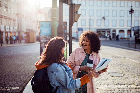 Two friends reading a map on a sunny european city street