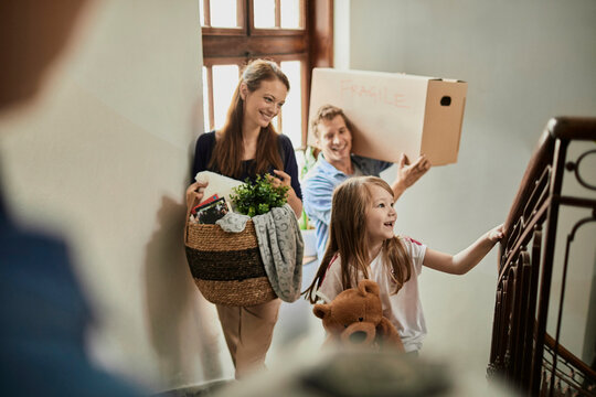 Parents and child moving boxes up apartment stairs