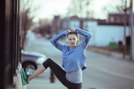 Young woman stretching before run on city street