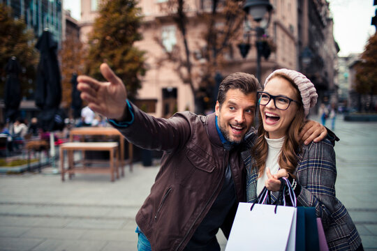 Happy couple shopping and sightseeing on city street