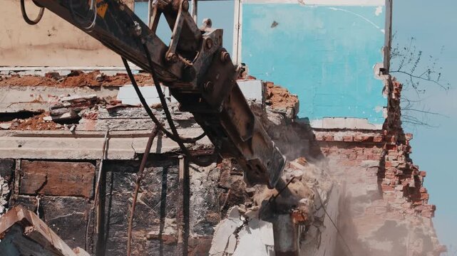 Excavator hydraulic hammer breaking concrete structure during demolition work