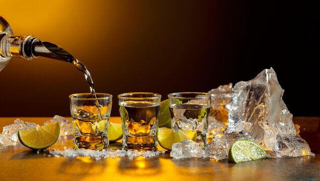 The tequila is poured from the bottle into shot glasses.