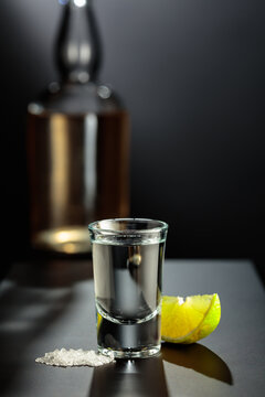 Mexican Tequila shot with lime and salt on black table.