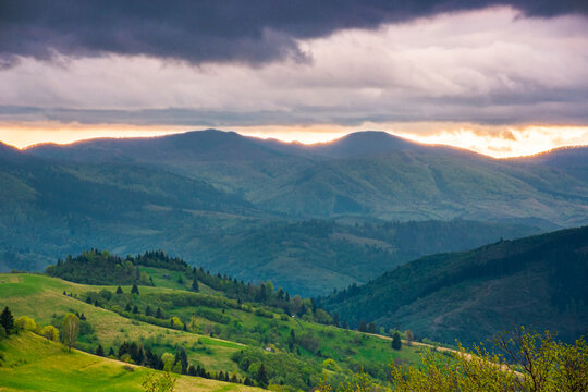 mountainous countryside scenery in the afternoon. gloomy sky view above the valley. green fields and trees on the hills. volatile nature scenery of carpathian mountains