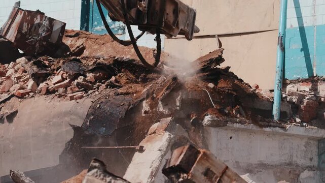 Excavator breaking concrete with hydraulic hammer during demolition close up