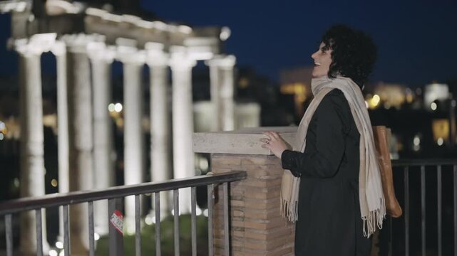 Excited happy woman spread hands wide open rotating enjoying a night tour of Roman forum with background view of Tample of Saturn in Rome, Italy, slow motion