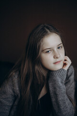 Fototapeta premium Teenage girl. Studio portrait, brown background. Young woman is looking straight at camera. Portrait