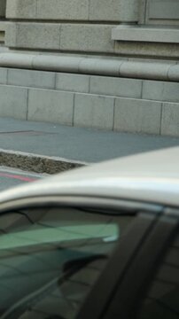 Vertical video: Opening showing jogger running pink top red tights crossing road passing silver car