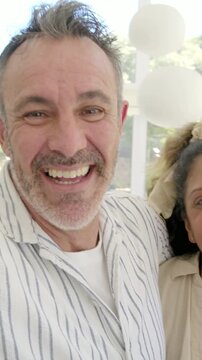 Vertical video: Raising phone, couple leaning and laughing, looking up at home, necklaces shown