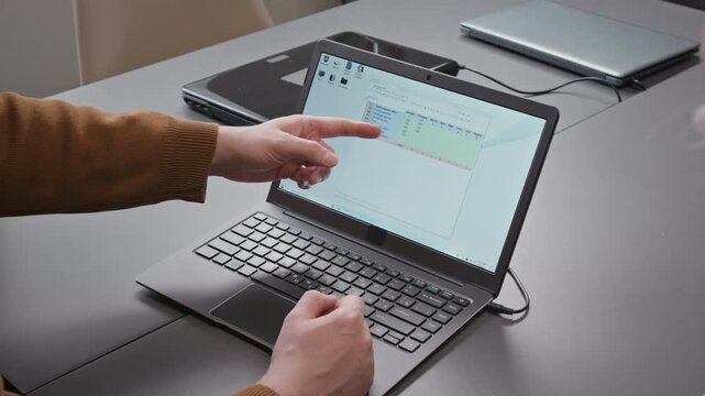 Over shoulder close up shot of hands pointing at laptop screen with male teacher explaining spreadsheets software to group of unrecognizable people in computer literacy class, copy space