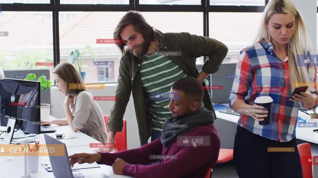 Seated man pointing at laptop while coworker leaning, advising in tech hub, social icons animating