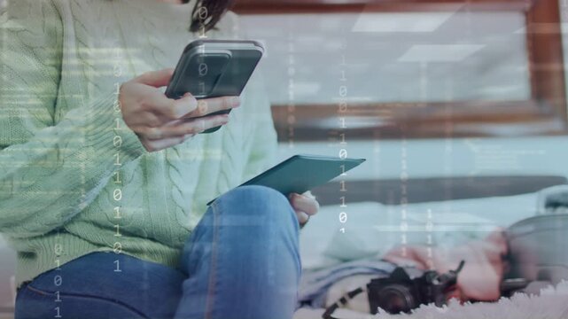 Woman tapping phone, inspecting passport preparing trip on bed while binary overlay revealing data