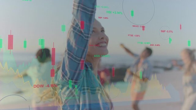 Woman raising arm after pan on beach, semi-transparent finance layer overlaying charts over group