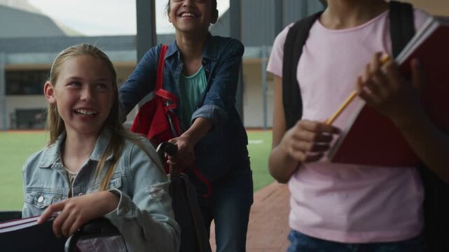 3 girls walking between classes pushing wheelchair carrying notebooks camera closing brain pulsing