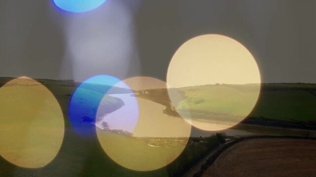 Translucent bokeh appearing, shifting, overlapping and fading, revealing winding river and fields