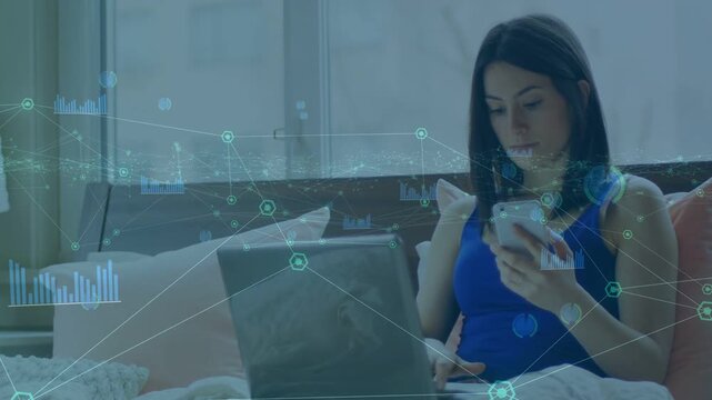 Woman tapping phone and scrolling on bed, switching to laptop, monitoring tech nodes and charts