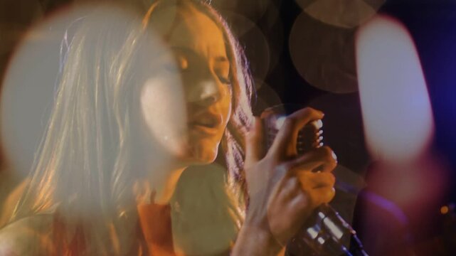 Female singer stepping to retro mic and singing, layered bokeh lights shaping music performance