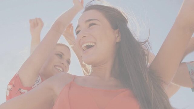 Coral-top woman raising arms and leading peers laughing, promoting summer brand with lens flare