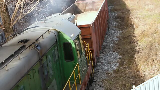 An open freight car loaded with bulk materials moves along the railway. Industrial rail freight transportation. Transportation of clay and sand in open rail cars.