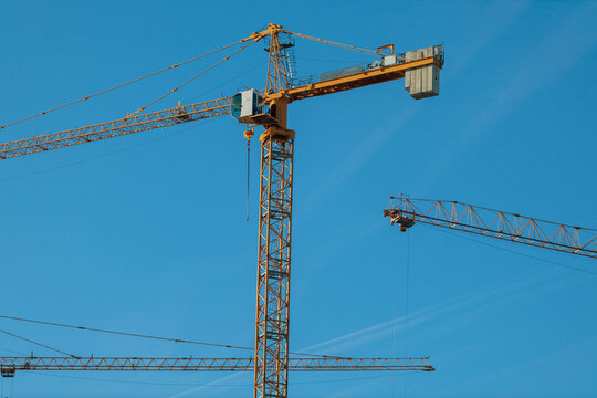 Construction cranes work under blue sky