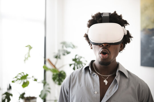 A young man wearing a virtual reality headset is experiencing something immersive. His mouth is open in surprise or awe as he engages with the digital world.