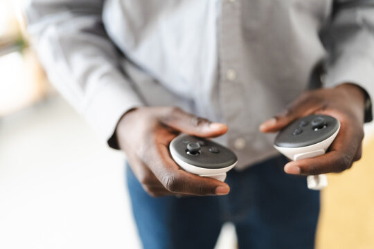A person holds two white and black controllers, ready to engage in a virtual reality experience.