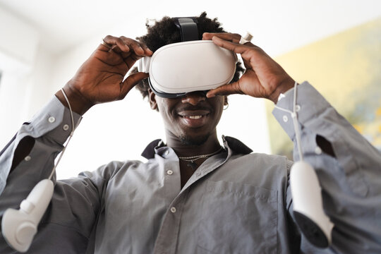 A young man smiles as he puts on a virtual reality headset and controllers, ready to explore new digital worlds.