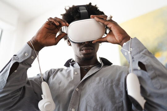 A young man wearing a virtual reality headset and holding controllers immerses himself in a digital world.