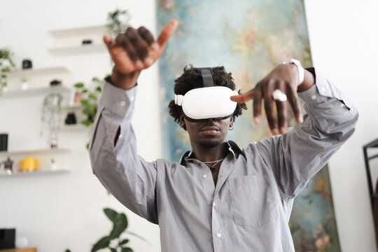 A young man wearing a virtual reality headset interacts with a digital world, his hands gesturing as he experiences immersive technology.