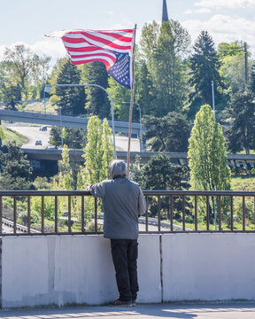 Protestor waving upside-down American Flag on I-5 overpass in Tacoma, Washington portrait