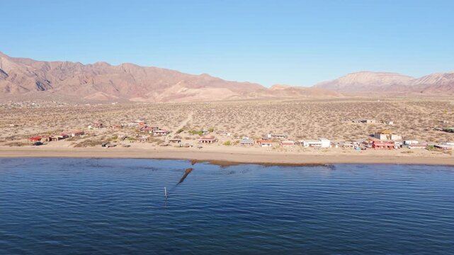 Aerial views show Bahia De Los Angeles at sunrise, with beach camps and distant mountains in Baja California, Mexico.