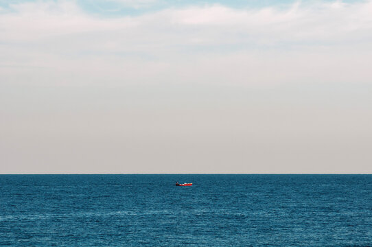 Bright Day With a Small Boat in the Ocean Far From the Shore