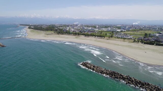 【ドローン空撮動画】海上の消波ブロックから岩瀬浜と春の立山連峰を見渡す旋回飛行