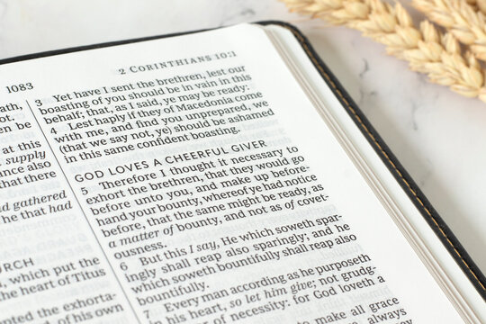 God loves a cheerful giver text in holy bible book. Christian biblical concept of tithing, offering, blessing, and generosity.