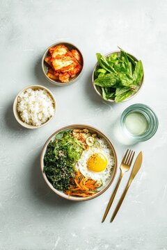 Top down wellness meal planner lay kimchi greens rice bowl water glass