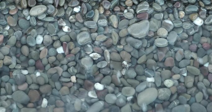 Calm ocean waves idyllic shore beach with turquoise water and pebbles, close-up of sea pebbles with calm sea waves