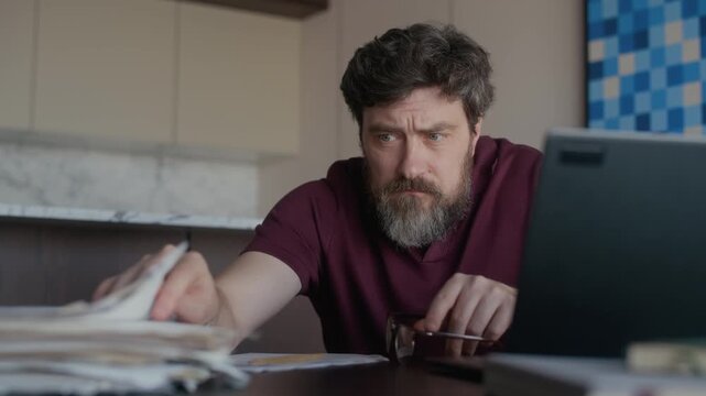 Exhausted mature adult Caucasian male author looking through papers and getting stuck while writing novel, creative block concept