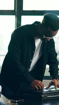 Black man, business and packing with bag in office, finish up and complete project with mobile. Leaving, professional and person in workplace with briefcase, phone and walk at end of day schedule