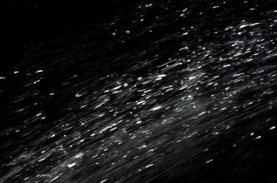 Water droplets move quickly in dark background at night or during a performance for effect
