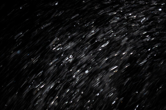 Water droplets move quickly in dark background at night or during a performance for effect