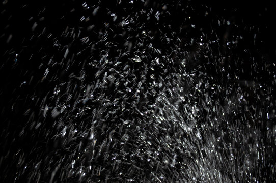 Water spray creates droplets in a dark background during the evening