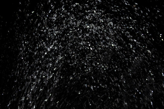 Water spray creates droplets in a dark background during the evening