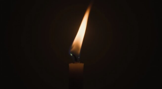 Lit candle in the dark with a black background