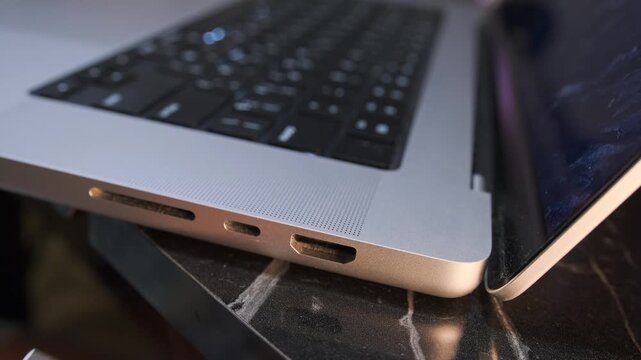 Hand pulling USB C cable out of laptop port, close-up of disconnecting device from modern notebook, removing connection during workflow on desk. Disconnecting USB-C cable from laptop 