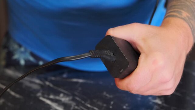 Close-up of hands inserting cable into drone unit port, preparing device for power supply or data connection, modern UAV setup and maintenance process in technical workspace