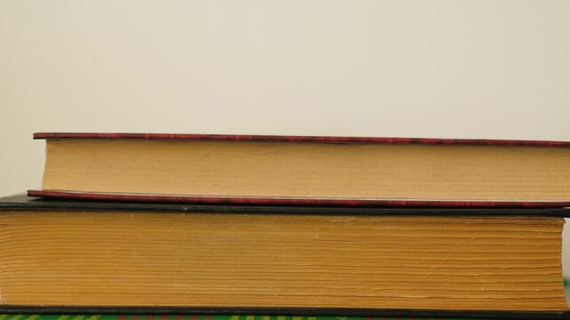 Close-up of stacking old vintage books on top of each other. Side view of weathered paper texture and book edges forming a stack against a plain background