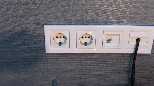 hand pulling ethernet cable close-up view, unplugging network connector from wall socket panel, internet connection interruption, home networking setup, technology and communication process